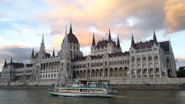 A photograph of a cruise passing a historic building.